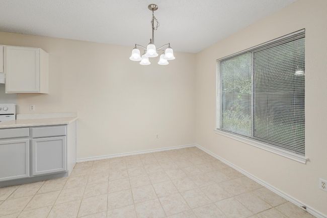 Unfurnished dining area featuring a chandelier and baseboards | Image 8