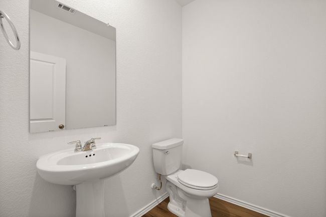 Half bathroom with visible vents, toilet, a sink, wood finished floors, and baseboards | Image 4