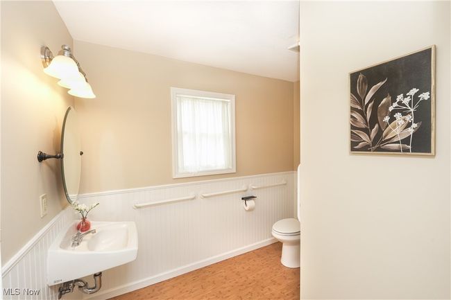 Bathroom featuring wainscoting, wood finished floors, a sink, and toilet | Image 17