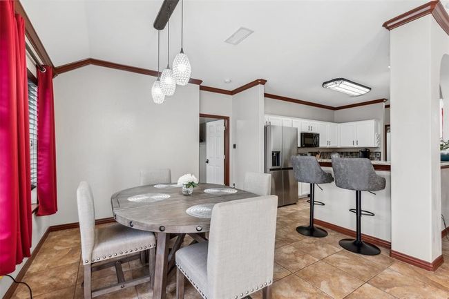 Dining space with visible vents, baseboards, lofted ceiling, ornamental molding, and light tile patterned floors | Image 14