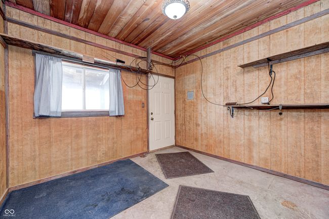 basement featuring baseboards, wooden walls, and wood ceiling | Image 8