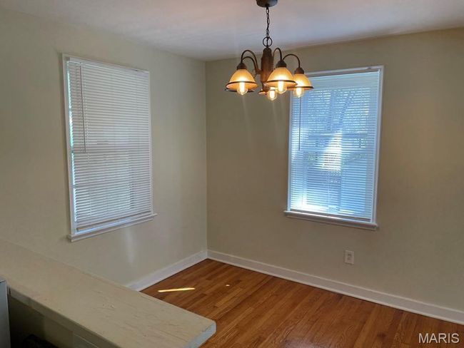 Unfurnished dining area with baseboards, wood finished floors, and an inviting chandelier | Image 7