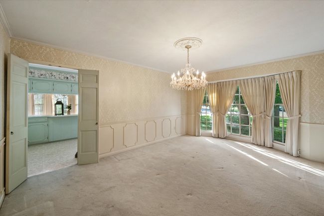 Wool carpeted dining room with crystal chandelier, wallpapered walls, wainscoting, and gorgeous wood bay window | Image 7