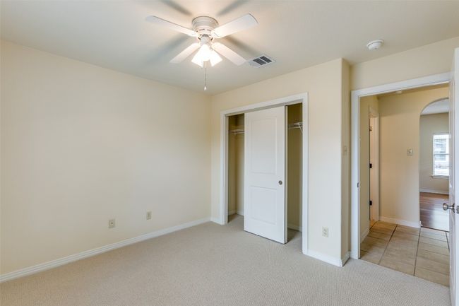 Unfurnished bedroom featuring arched walkways, a closet, light colored carpet, and ceiling fan | Image 19