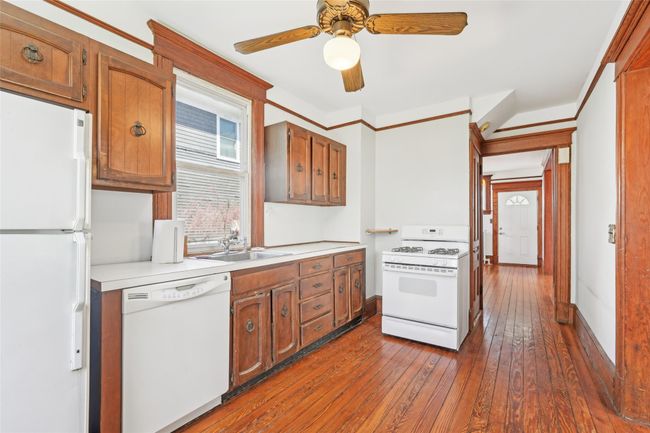 Kitchen with ceiling fan, dark wood finished floors, white appliances, light countertops, and a sink | Image 12