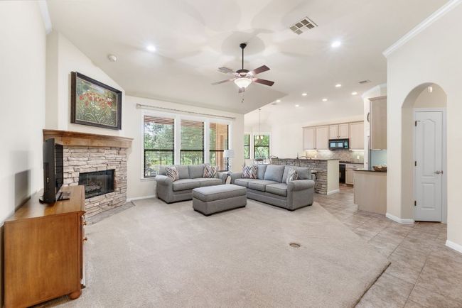 Living area featuring a ceiling fan, a stone fireplace, vaulted ceiling, recessed lighting, and light tile patterned floors | Image 6