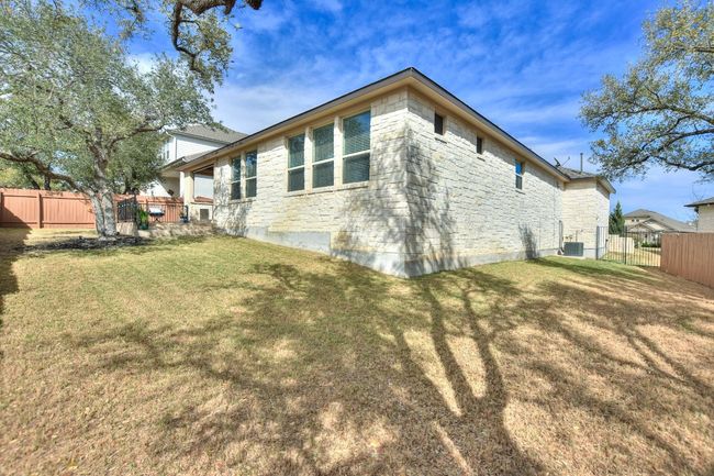 View of side of property featuring fence, stone siding, central AC, and a lawn | Image 34