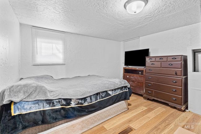 Bedroom featuring a textured wall, light wood finished floors, and a textured ceiling | Image 14