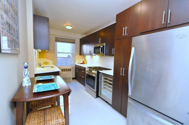Fully renovated Eat-in-Kitchen has custom mocha colored cabinets, Quarts counters and stainless steel appliances including a wine cooler, dishwasher, microwave, range and refrigerator. | Image 13