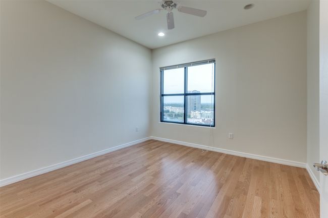 The spacious primary bedroom is a true retreat, featuring rich hardwood floors, an abundance of natural light streaming through a large picture window, and a private en-suite bath—creating the perfect blend of comfort, elegance, and serenity. | Image 26