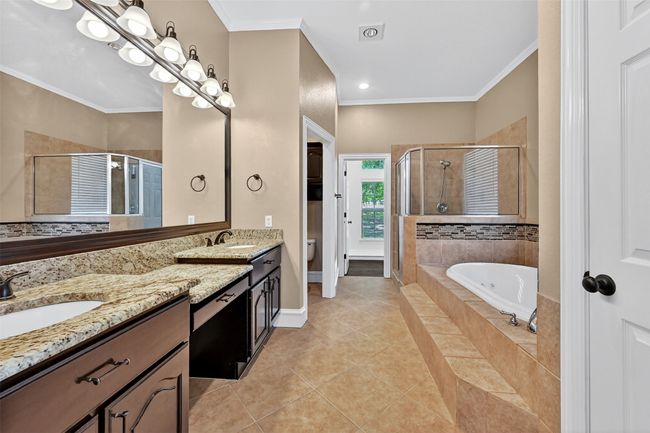 Full bathroom featuring double vanity, a shower stall, a garden tub, ornamental molding, and toilet | Image 24