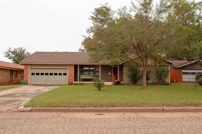 View of front facade with a garage, a porch, and a front yard | Image 1