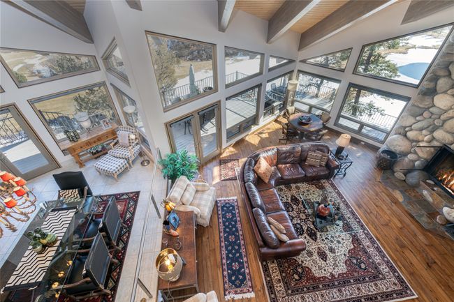 Living room featuring hardwood / wood-style flooring, a towering ceiling, beam ceiling, and a stone fireplace | Image 23