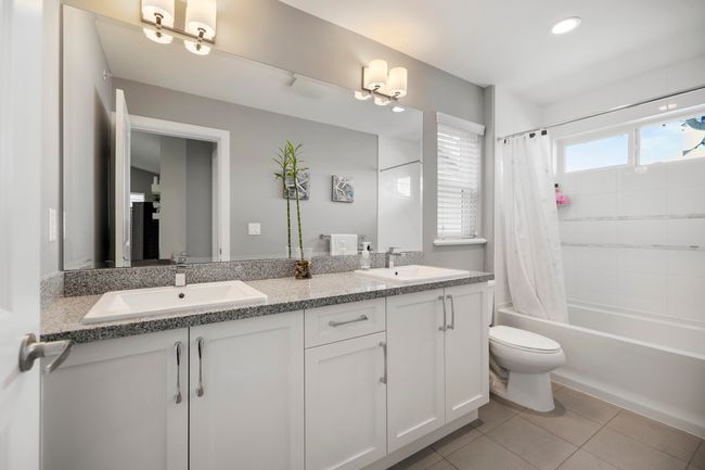Bathroom with tile patterned floors, shower / bathtub combination with curtain, toilet, and a sink | Image 26