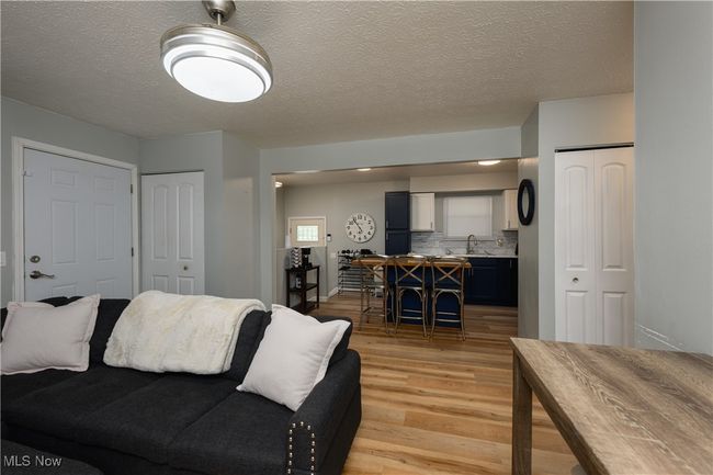 Living area with light wood finished floors and a textured ceiling | Image 6