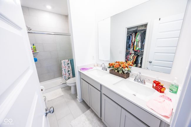 bathroom with double vanity, a shower stall, toilet, tile patterned floors, and a spacious closet | Image 13