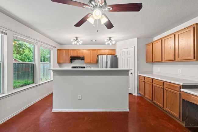 The bright dining area includes a ceiling fan and a built-in desk area. | Image 8