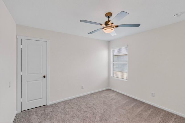 Empty room with light colored carpet, ceiling fan, baseboards, and a smoke detector | Image 28