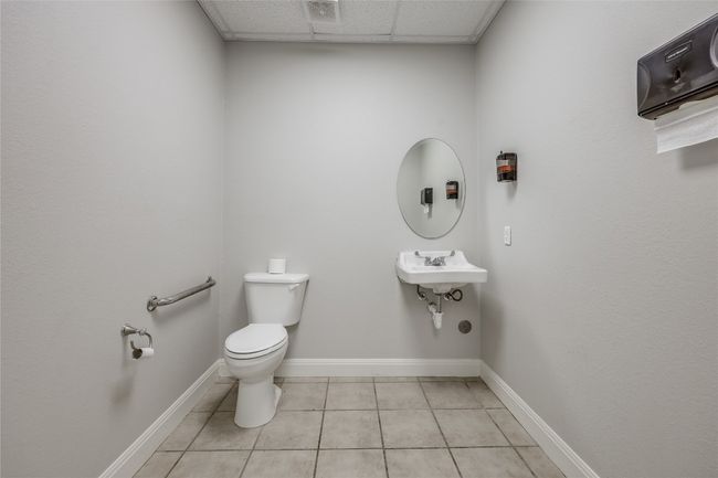 Bathroom with tile patterned floors, a sink, a drop ceiling, toilet, and baseboards | Image 36