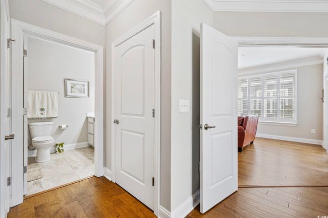 Corridor with crown molding, wood finished floors, and baseboards | Image 15