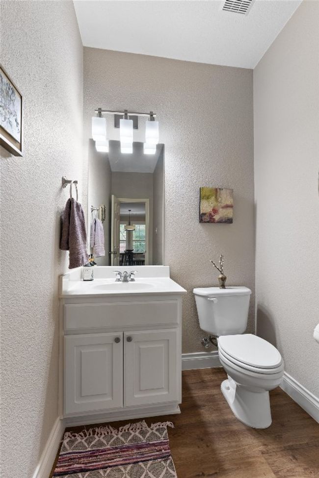Half bathroom featuring vanity, toilet, wood finished floors, baseboards, and a textured wall | Image 14