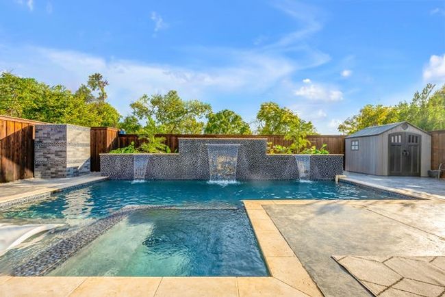 View of swimming pool featuring an in ground hot tub, pool water feature, and a shed | Image 15