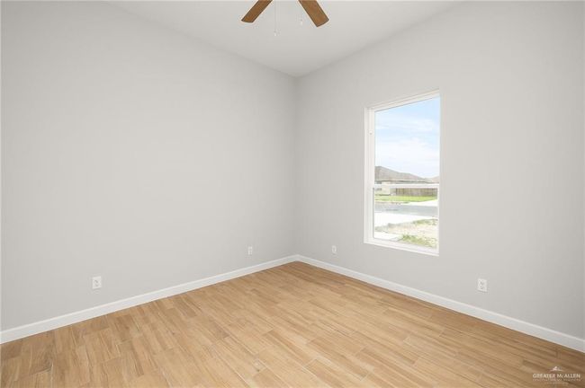 Empty room with ceiling fan, light wood-type flooring, and baseboards | Image 10