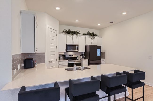 Kitchen featuring stainless steel appliances, visible vents, a sink, a peninsula, and a kitchen bar | Image 11