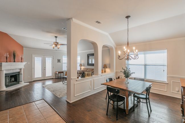 Dining room with visible vents, dark wood-type flooring, a fireplace with raised hearth, and vaulted ceiling | Image 5