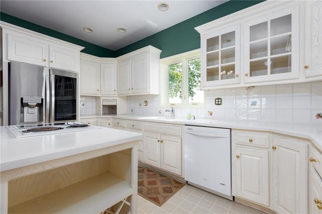 Kitchen with white cabinets, backsplash, white appliances, and light tile patterned floors | Image 42