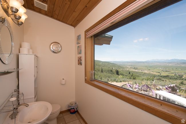 Bathroom with tile patterned floors, wood ceiling, visible vents, toilet, and a mountain view | Image 68