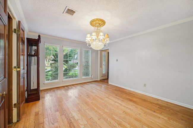 This formal dining room features hardwood floors, large windows with shutters, and a central chandelier, creating a bright and elegant space. | Image 5