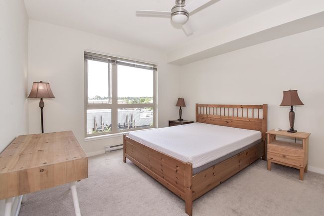 Bedroom with light colored carpet, a baseboard radiator, and a ceiling fan | Image 10