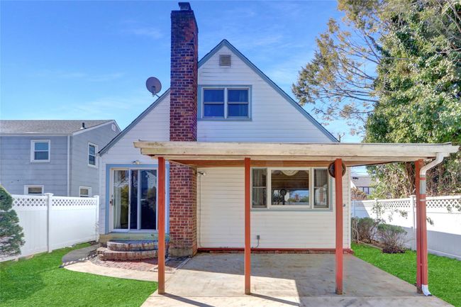 Rear view of house with brick siding, a lawn, a chimney, a fenced backyard, and a patio | Image 21