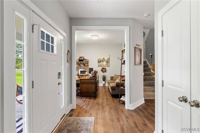 Foyer featuring light wood-style floors, baseboards, visible vents, and stairway | Image 7