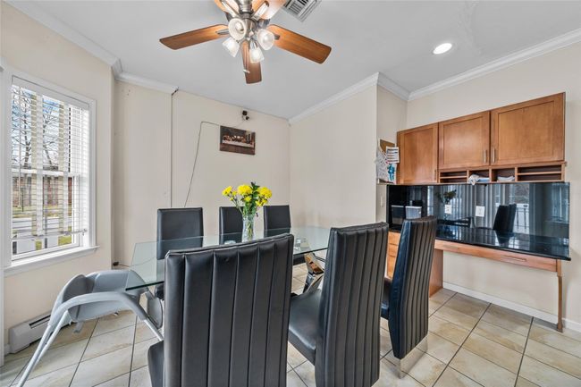 Dining room with crown molding, ceiling fan, visible vents, and light tile patterned floors | Image 8