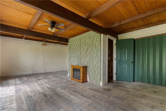 Unfurnished living room with wood finished floors, ceiling fan, a fireplace, and wood ceiling with exposed beams | Image 24