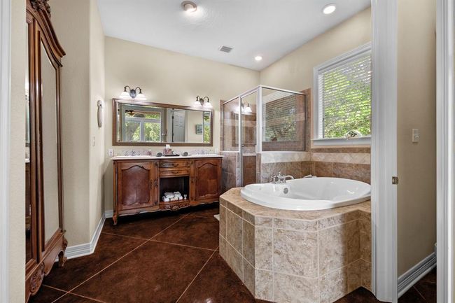 Antique-style double vanity with stone-topped cabinets, twin sinks, and oversized mirror—perfect for morning routines and shared use. | Image 26