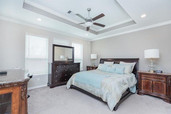 Spacious bedroom with a tray ceiling, featuring a ceiling fan and recessed lighting. | Image 16