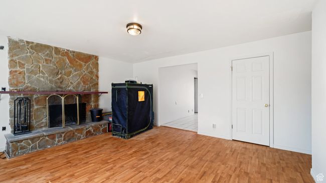 Unfurnished living room featuring a stone fireplace, baseboards, and wood finished floors | Image 4