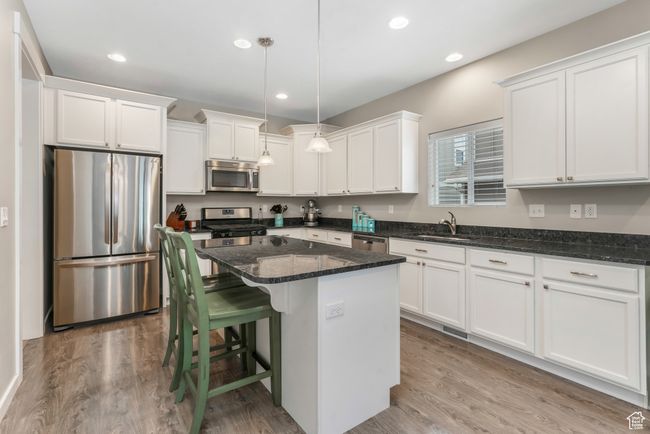 Kitchen featuring white cabinets, wood finished floors, a sink, and stainless steel appliances | Image 7