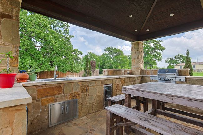 View of patio featuring grilling area, outdoor dining area, exterior kitchen, a sink, and fence | Image 25