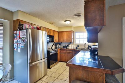 Kitchen featuring stainless steel appliances, sink, kitchen peninsula, tasteful backsplash, and a textured ceiling | Image 3