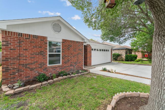 Single story home featuring concrete driveway, brick siding, an attached garage, and a front lawn | Image 4