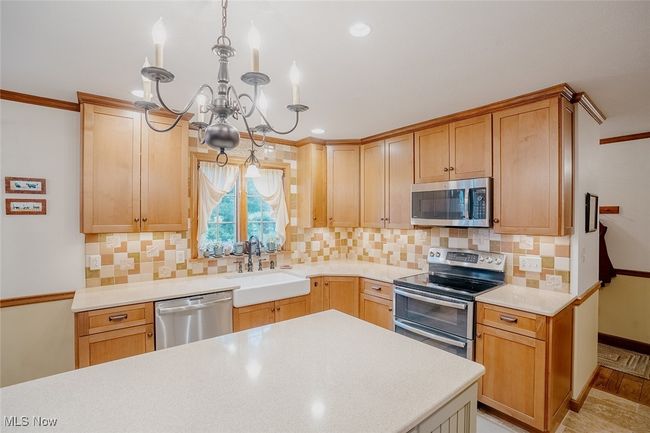 Main kitchen featuring stainless steel appliances, a chandelier, light countertops, backsplash, and recessed lighting | Image 7