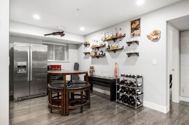 Bar with baseboards, recessed lighting, wood finished floors, stainless steel fridge, and a bar | Image 31