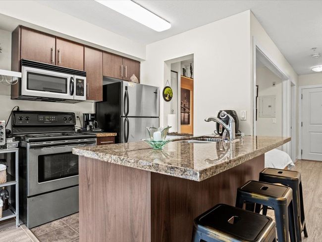 Kitchen with stainless steel appliances and a breakfast bar area | Image 8