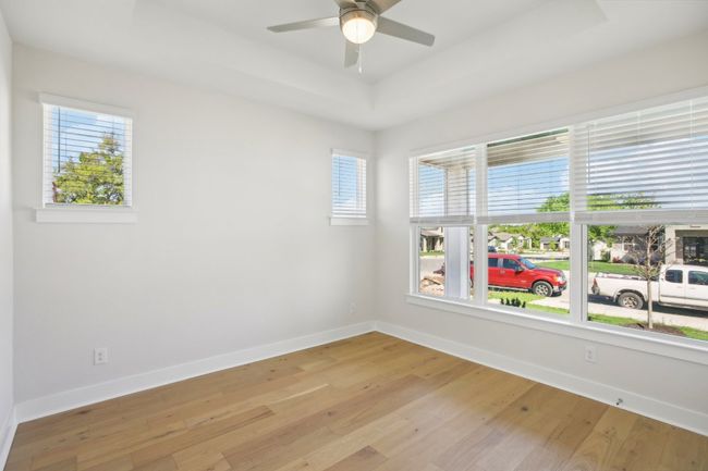 Empty room featuring a tray ceiling, light wood-type flooring, baseboards, and a ceiling fan | Image 8