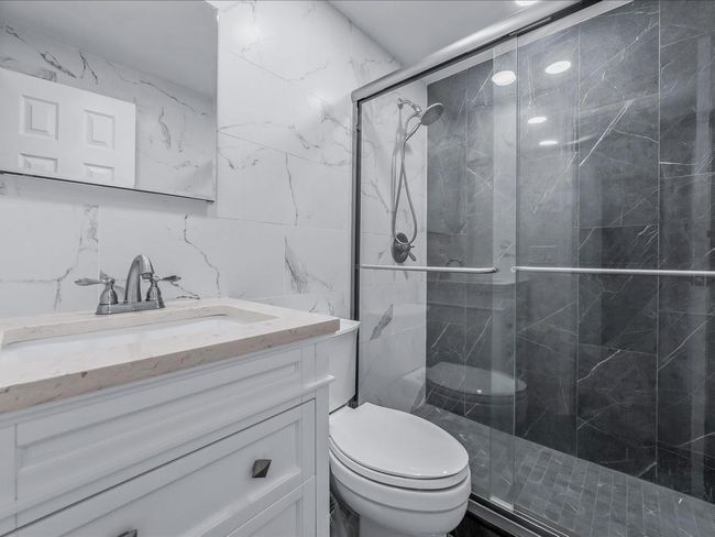Full bath with tile walls, vanity, toilet, and a marble finish shower | Image 19