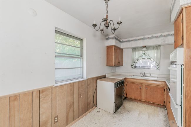 Kitchen with wainscoting, oven, a chandelier, light countertops, and dishwasher | Image 7